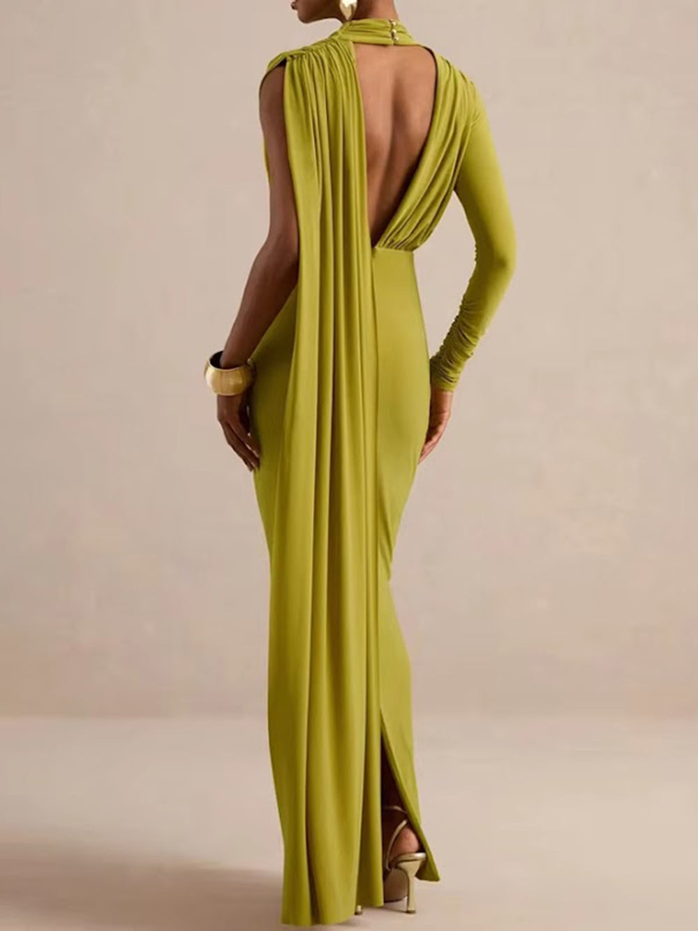 Back view of the chartreuse olive maxi dress with open back, one long sleeve, and flowing draped panel