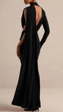 Back view of the black dress showing an open back and long cascading shoulder drape