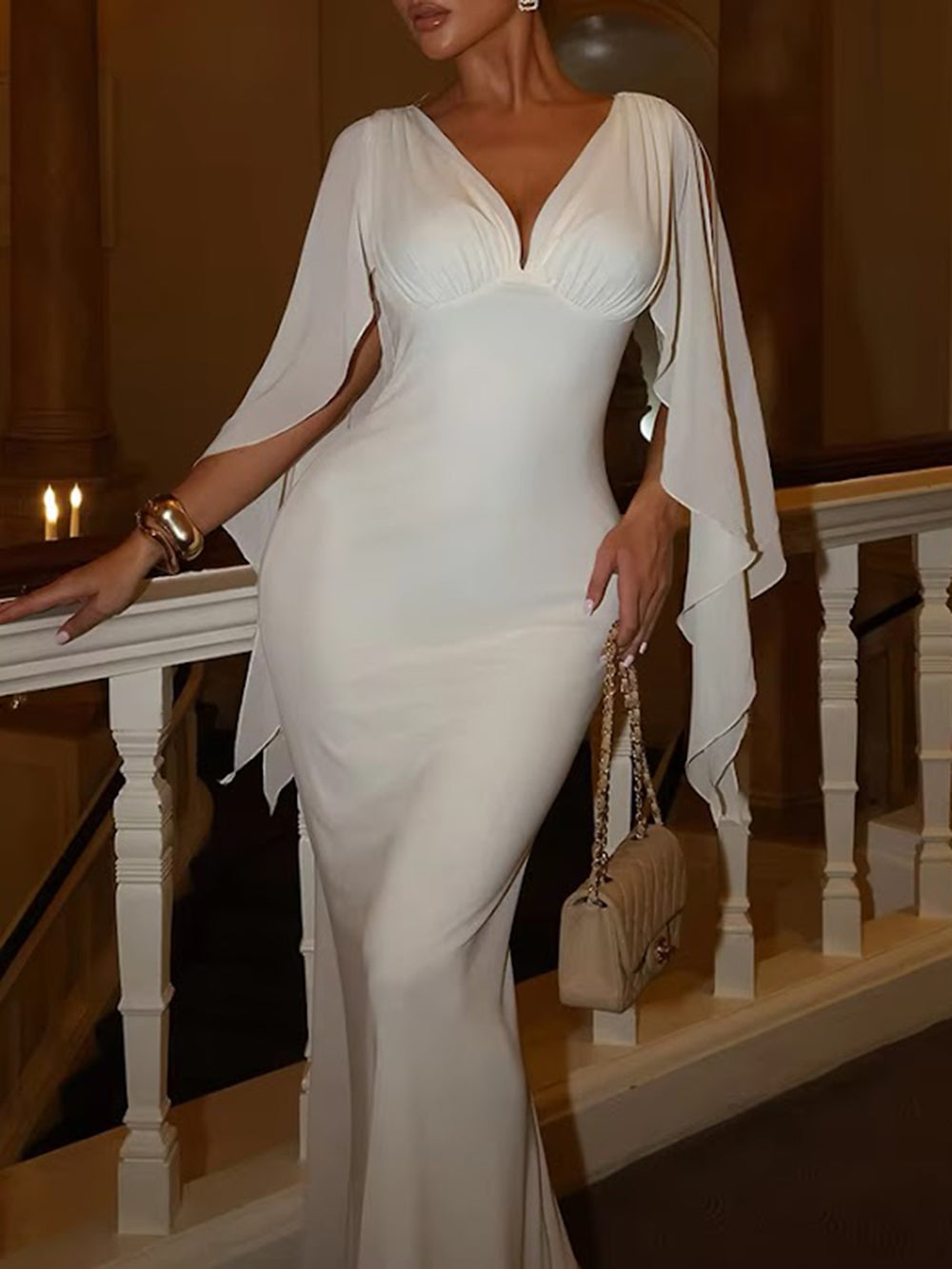Model wearing the ivory Celeste gown with a deep V neckline and long flowing cape sleeves