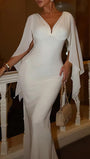 Model wearing the ivory Celeste gown with a deep V neckline and long flowing cape sleeves