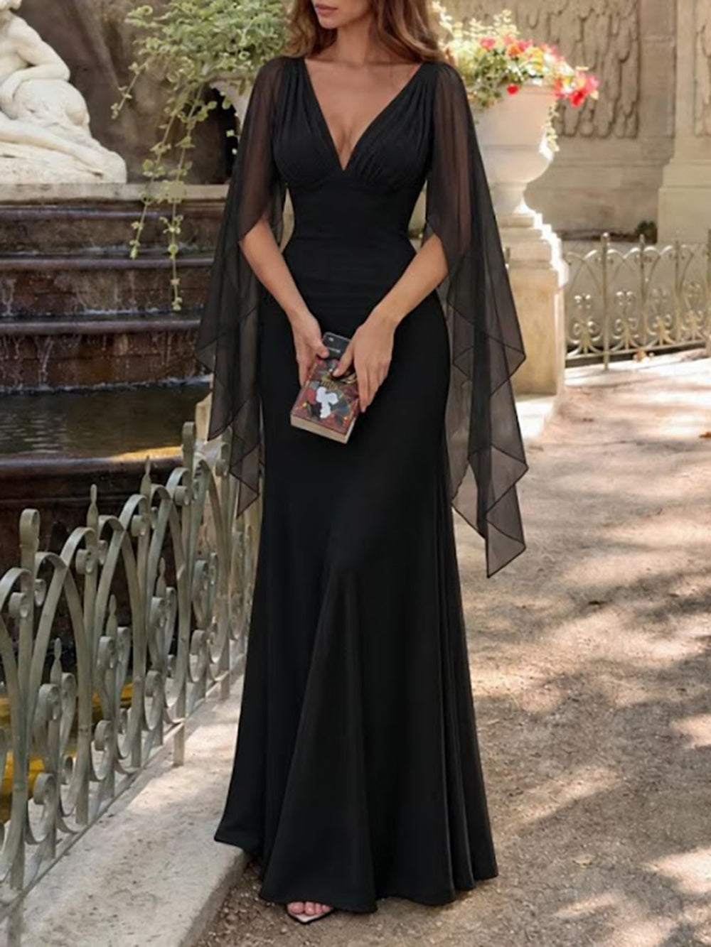 Full-length outdoor view of the black Celeste gown with a fitted bodice and fluid floor-length hem
