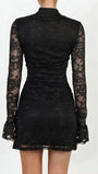 Back view of the black mini dress showing fitted floral lace and short flared hem