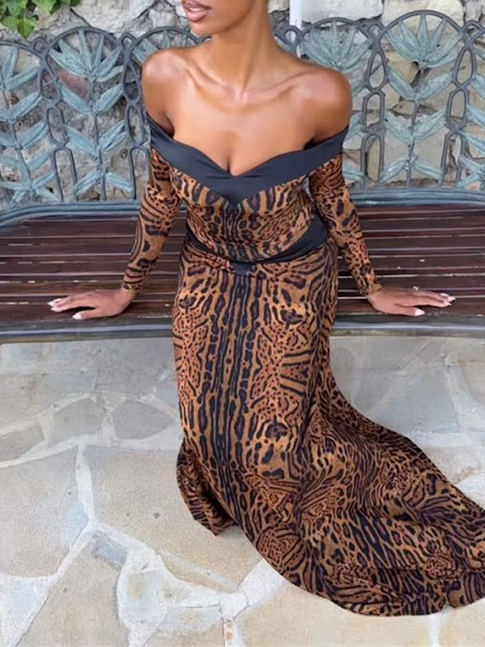 Seated model wearing the printed gown with fitted sleeves and a long fluid skirt