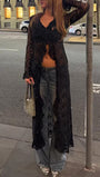 Model wearing the black longline lace blouse open over dark separates in a city setting