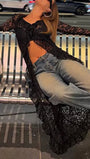 Seated view of the black longline lace blouse layered over denim