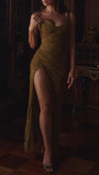 Model wearing the olive maxi dress in evening lighting with gathered shaping and a dramatic leg slit