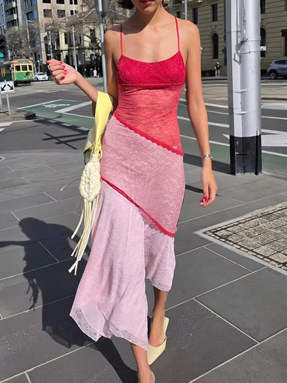 Model wearing the pink and red lace midi dress outdoors with an asymmetric flowing hem