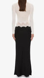 Back view of the monochrome maxi dress with white long-sleeve bodice, lace waist trim, and black floor-length skirt