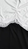 Close up of the white bodice and black skirt joined by scalloped floral lace at the waist