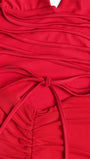 Close up of crimson fabric gathered into soft folds with a narrow matching tie
