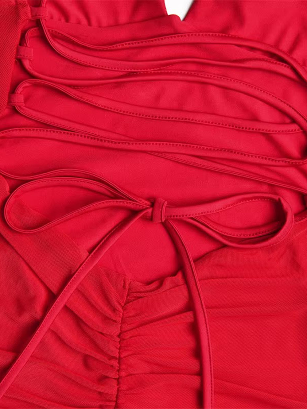 Close up of crimson fabric gathered into soft folds with a narrow matching tie